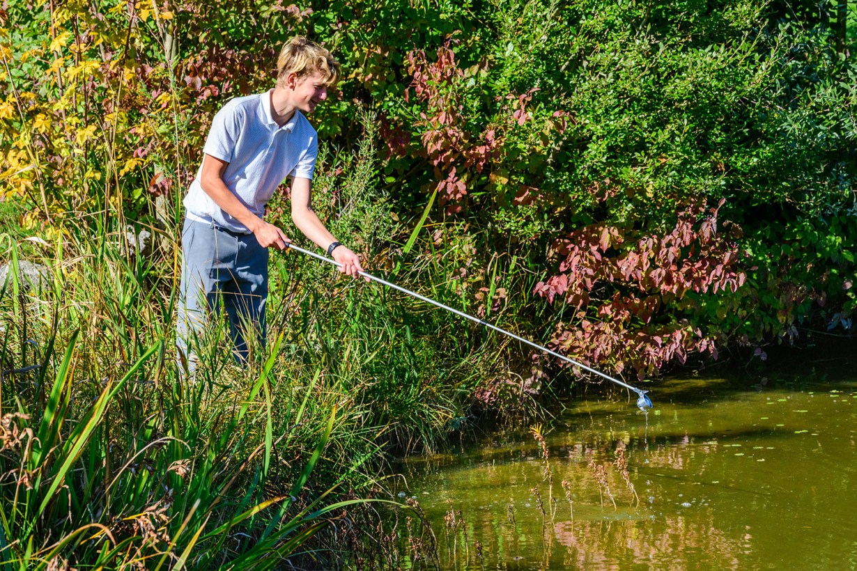a man retrieving a golf ball in the water