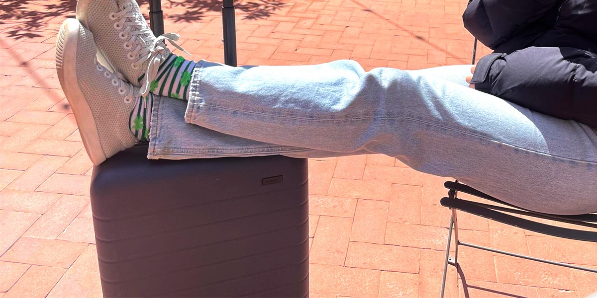 Person siiting in chair with feet resting on top of Away Carry-On
