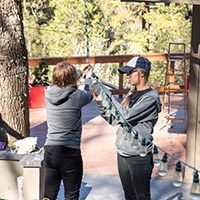two women hanging solar Christmas lights